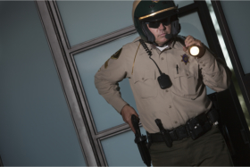 A policeman holding a flashlight while drawing a gun