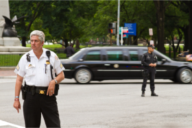 A security officer with a limousine and other officer in the background